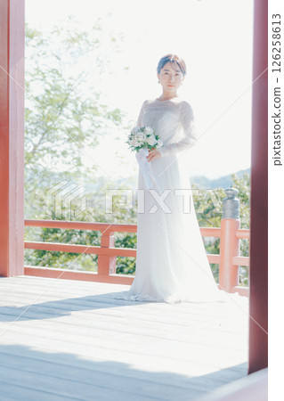 一位身著婚紗的女子從山上的神社俯瞰小鎮的畫像 一位身著婚紗的女子從山上的神社俯瞰小鎮的畫像 126258613