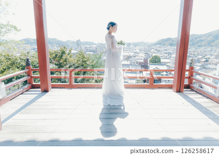 Portrait of a woman in a wedding dress looking out over the town from a shrine on a hill Portrait of a woman in a wedding dress looking out over the town from a shrine on a hill 126258617
