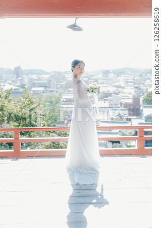 一位身著婚紗的女子從山上的神社俯瞰小鎮的畫像 126258619