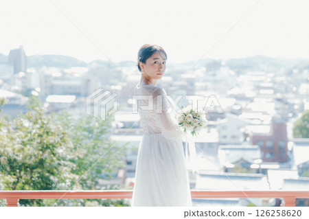 一位身著婚紗的女子從山上的神社俯瞰小鎮的畫像 126258620