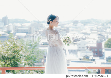 一位身著婚紗的女子從山上的神社俯瞰小鎮的畫像 126258621