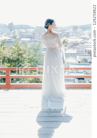 一位身著婚紗的女子從山上的神社俯瞰小鎮的畫像 一位身著婚紗的女子從山上的神社俯瞰小鎮的畫像 126258622