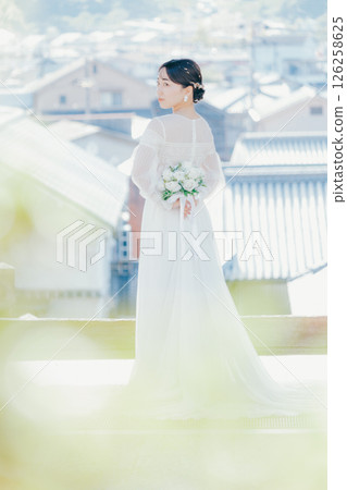 一位身著婚紗的女子從山上的神社俯瞰小鎮的畫像 一位身著婚紗的女子從山上的神社俯瞰小鎮的畫像 126258625