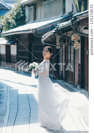 Portrait of a woman in a white wedding dress looking back in an old town 126258635