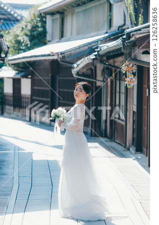 Portrait of a woman in a white wedding dress looking back in an old town 126258636