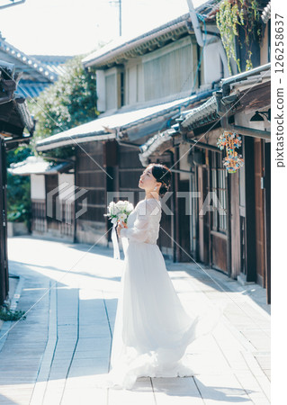 Portrait of a woman in a white wedding dress looking back in an old town Portrait of a woman in a white wedding dress looking back in an old town 126258637