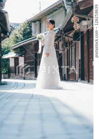 Portrait of a woman in a white wedding dress looking back in an old town 126258639
