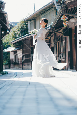 Portrait of a woman in a white wedding dress looking back in an old town 126258640