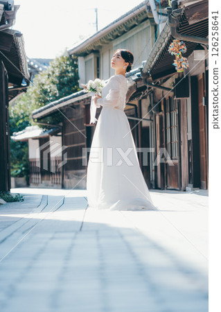 Portrait of a woman in a white wedding dress looking back in an old town Portrait of a woman in a white wedding dress looking back in an old town 126258641