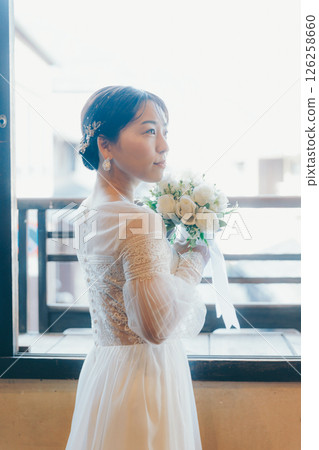 Profile of a woman in a wedding dress holding a bouquet and looking up at the sky Profile of a woman in a wedding dress holding a bouquet and looking up at the sky 126258660