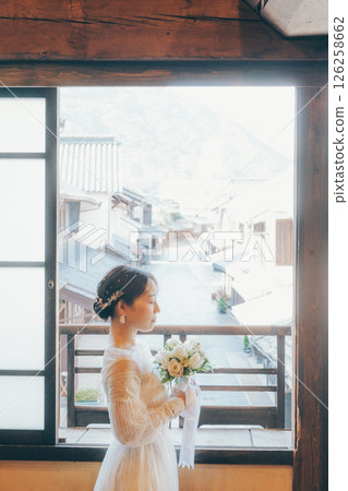 一位身穿婚紗、手捧花束、仰望天空的女子的側面像 126258662