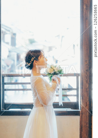 一位身穿婚紗、手捧花束、仰望天空的女子的側面像 126258665