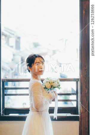 Profile of a woman in a wedding dress holding a bouquet and looking up at the sky 126258666