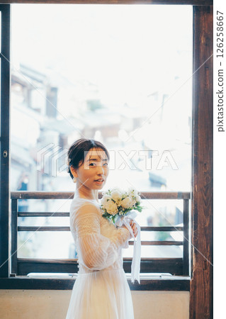 Profile of a woman in a wedding dress holding a bouquet and looking up at the sky 126258667