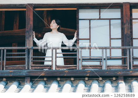 A woman in a wedding dress looking out from the second floor of a townhouse A woman in a wedding dress looking out from the second floor of a townhouse 126258689