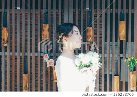 Portrait of a woman in a wedding dress standing against a background of Japanese decorations 126258706