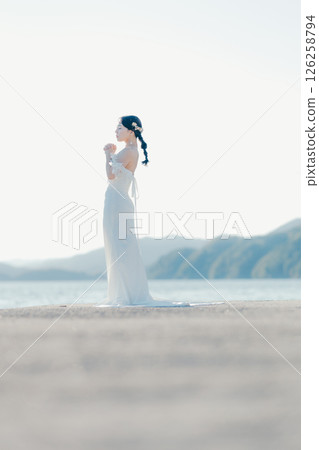 身穿婚紗的女子站在海灘背光下的肖像 126258794