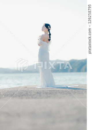 身穿婚紗的女子站在海灘背光下的肖像 身穿婚紗的女子站在海灘背光下的肖像 126258795