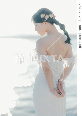 身穿婚紗的女子站在海灘背光下的肖像 126258797