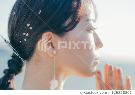Portrait of a woman in a wedding dress standing in the backlight at the beach Portrait of a woman in a wedding dress standing in the backlight at the beach 126258801