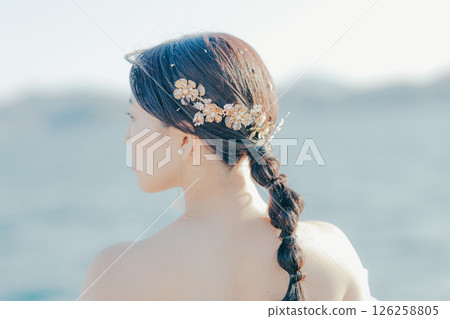 Portrait of a woman in a wedding dress standing in the backlight at the beach 126258805