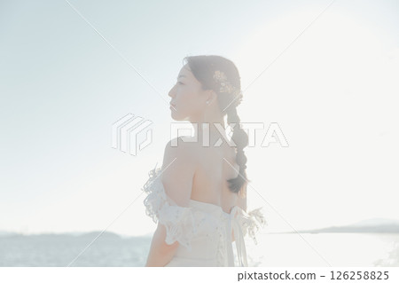 身穿婚紗的女子站在海灘背光下的肖像 身穿婚紗的女子站在海灘背光下的肖像 126258825