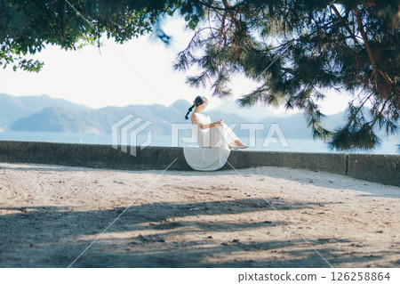 一位身穿婚紗的女子坐在陽光下，背景是一座山 126258864