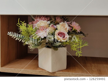 decorative floral arrangement in simple white container on wooden shelf in cozy interior setting. decorative floral arrangement in simple white container on wooden shelf in cozy interior setting. 126259491