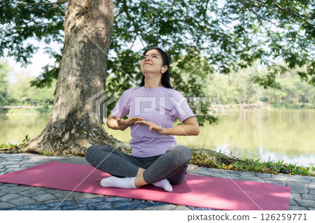 Wellness and Inner Peace. A woman meditating outdoors by a lake. Wellness and Inner Peace. A woman meditating outdoors by a lake. 126259771