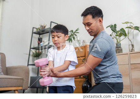 Family exercise session with father guiding son lifting weights 126259823