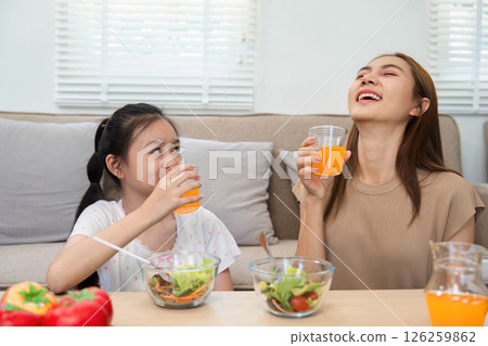 Wellness in family meals: Smiling mother and daughter sharing drinks Wellness in family meals: Smiling mother and daughter sharing drinks 126259862