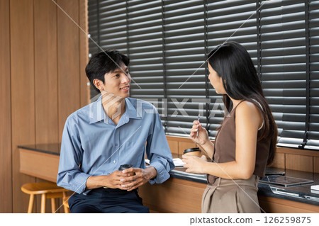 Business conversation over coffee. Two professionals discussing ideas in a relaxed office atmosphere. 126259875