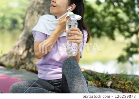 Wellness and Hydration. Woman enjoying refreshing water after outdoor exercise in nature. 126259878