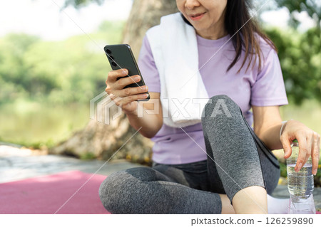Wellness and Mindfulness. Young woman practicing self-care with smartphone while relaxing outdoors. Wellness and Mindfulness. Young woman practicing self-care with smartphone while relaxing outdoors. 126259890