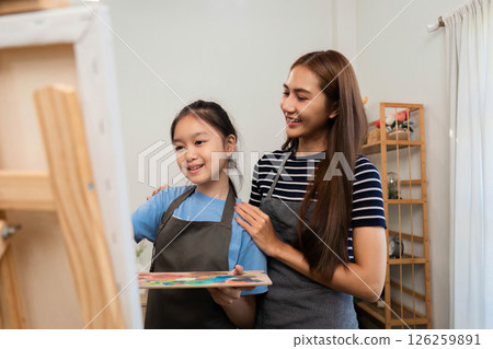 Family time focusing on creativity: Mother assisting daughter painting 126259891