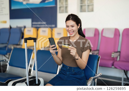 Travel preparation: woman using smartphone and credit card at airport Travel preparation: woman using smartphone and credit card at airport 126259895
