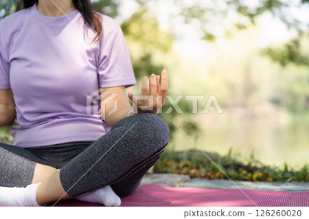 Wellness and Mindfulness. Woman practicing meditation outdoors by the water. 126260020