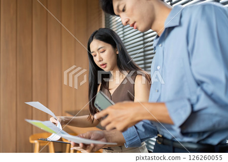 Business Interaction and Document Review. Professionals discussing project details in a stylish office setting. Business Interaction and Document Review. Professionals discussing project details in a stylish office setting. 126260055