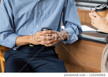 Business focus and connection. Close-up of hands holding coffee cups during a professional discussion. 126260068