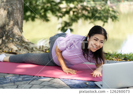 Wellness and Yoga. A woman smiling while practicing yoga outdoors, embracing fitness. Wellness and Yoga. A woman smiling while practicing yoga outdoors, embracing fitness. 126260073