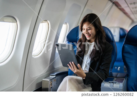 Business travel productivity with a woman using a tablet on a plane Business travel productivity with a woman using a tablet on a plane 126260082