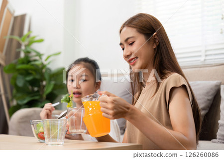 Wellness in daily routines: Mother and daughter enjoying juice and salad 126260086