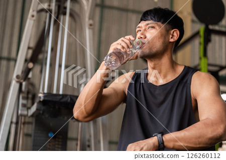 Fitness Hydration. Man drinking water during a gym workout to stay refreshed. Fitness Hydration. Man drinking water during a gym workout to stay refreshed. 126260112