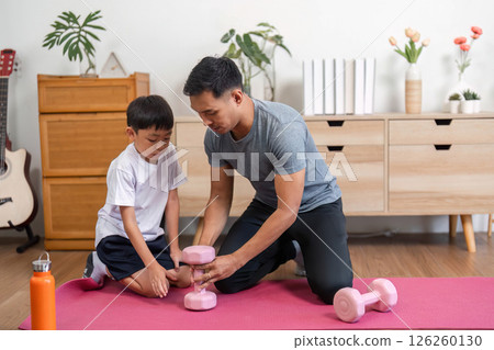 Family exercising together: Father and son using dumbbells at home Family exercising together: Father and son using dumbbells at home 126260130