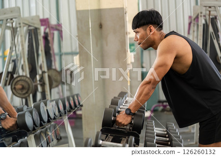 Fitness Focus. Man lifting weights while looking in mirror at gym. Fitness Focus. Man lifting weights while looking in mirror at gym. 126260132