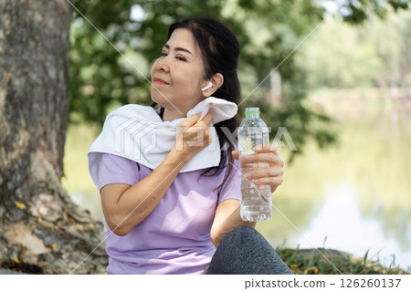 Wellness and Hydration. Woman refreshing herself with water after exercise outdoors. 126260137