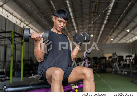 Fitness Training. Young man performing bicep curls with dumbbells in gym. Fitness Training. Young man performing bicep curls with dumbbells in gym. 126260185