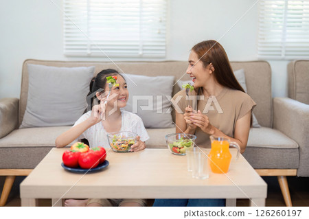 Wellness through healthy eating: Mother and daughter enjoying salads 126260197