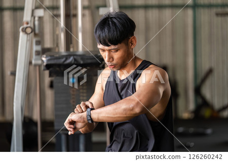 Fitness Tracking. Athlete checking smartwatch during workout in gym. Fitness Tracking. Athlete checking smartwatch during workout in gym. 126260242
