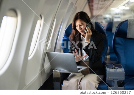 Business travel: Professional woman working on laptop during flight 126260257